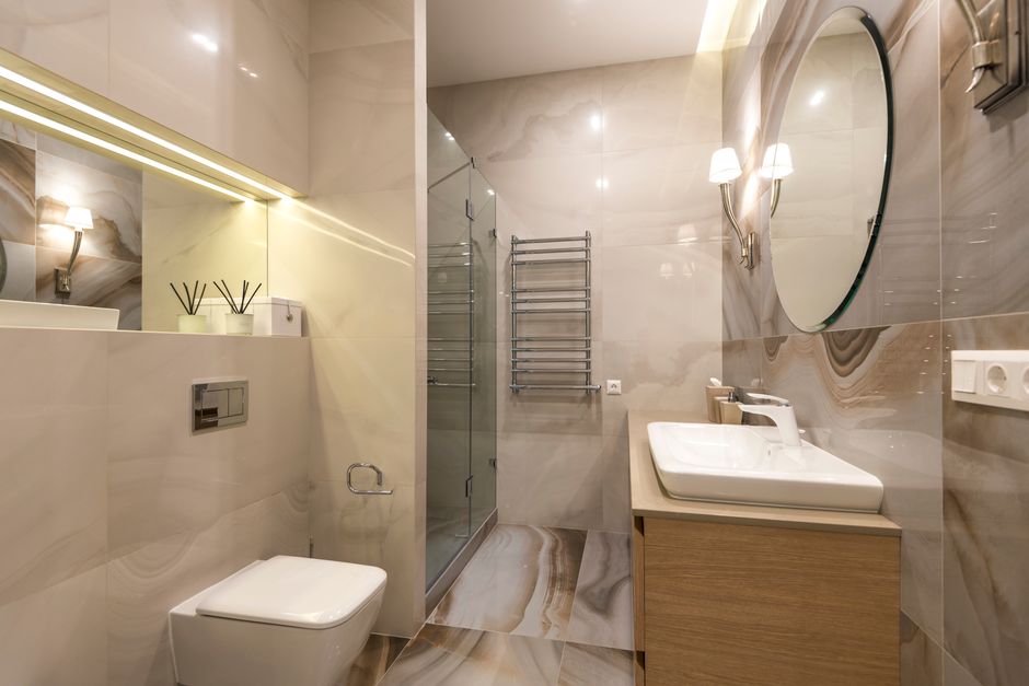 Baño de la habitación con ducha de vidrio y espejo redondo