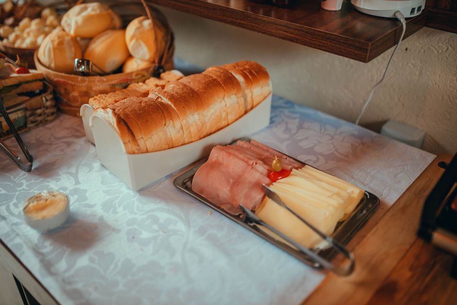 Mesa de desayuno con canasta de pan y bandeja de jamón y queso