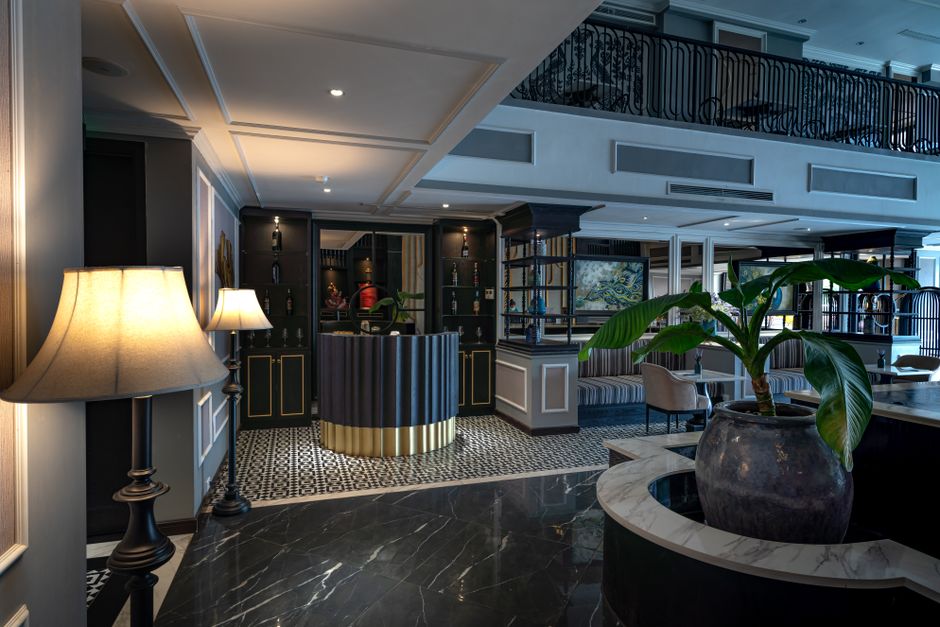 Recepción del hotel con lámparas de pie y piso de mármol